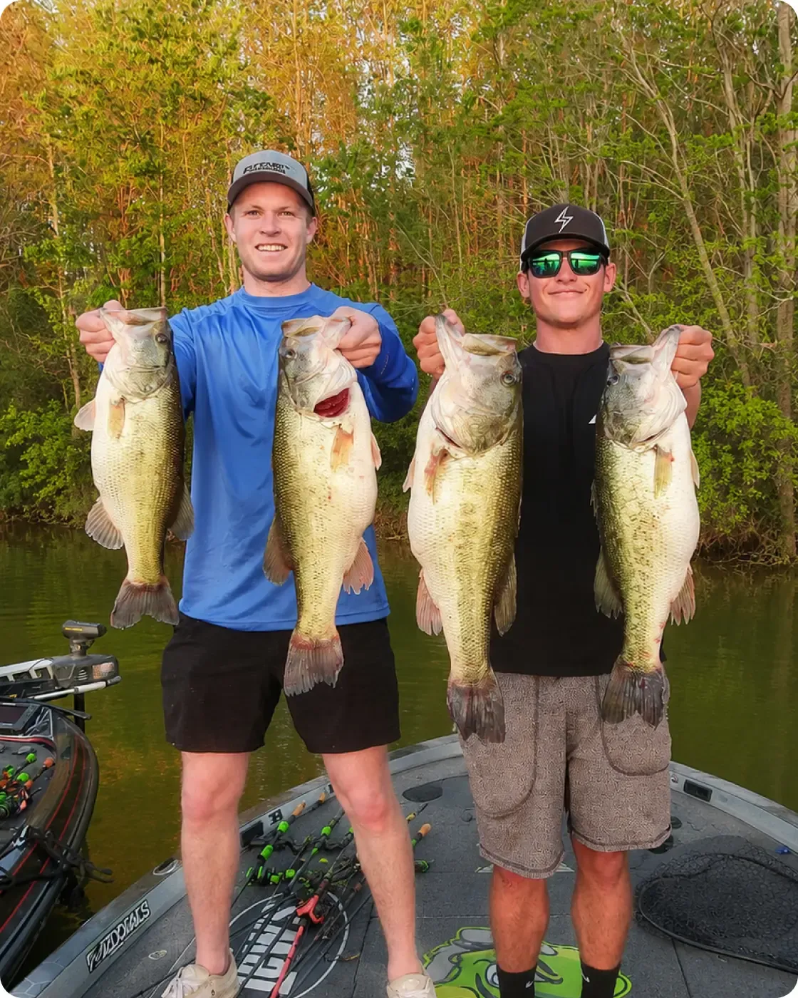 Noah and Fletcher holding largemouth bass on a boat